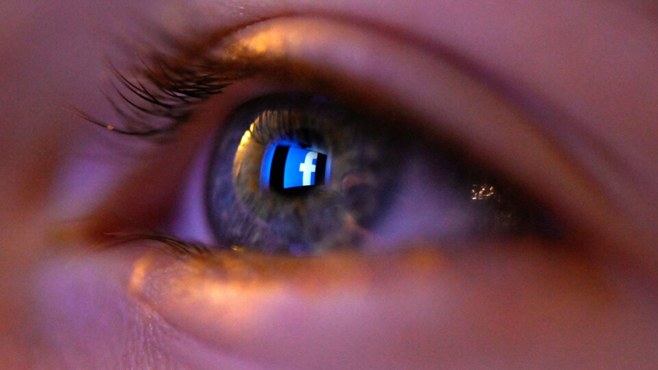 Un œil humain dans lequel on peut voir le reflet du logo de Facebook.