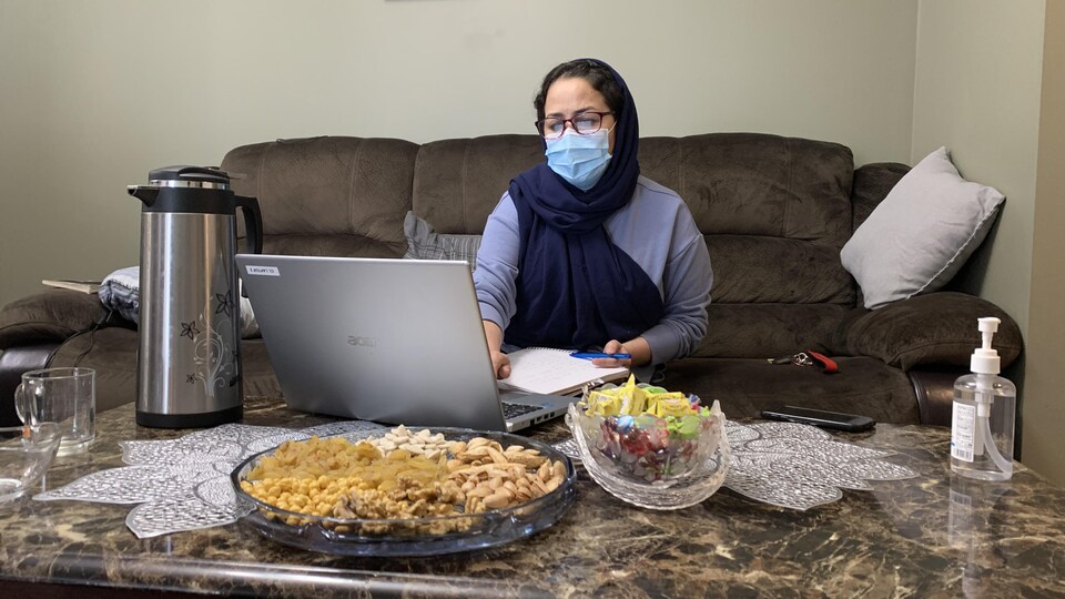 Fahima Yaqubi assise dans son salon devant un ordinateur.