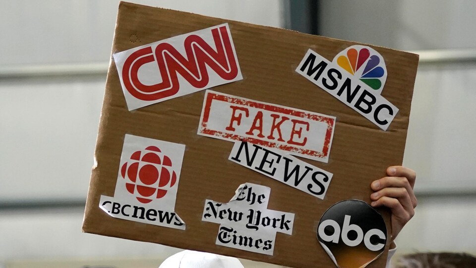 Un partisan du président Donald Trump brandit une pancarte associant les fausses nouvelles à des médias tels que CNN, CBC News et le New York Times.
