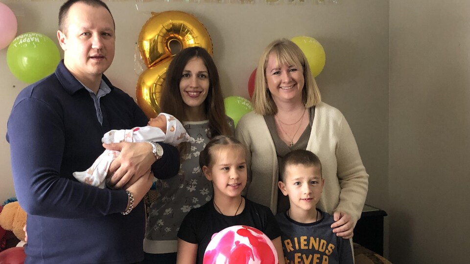 Une famille d'Ukrainiens et leur traductrice prennent la pose pour une photo.