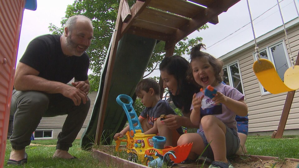 Un couple joue avec ses deux enfants dans le jardin.