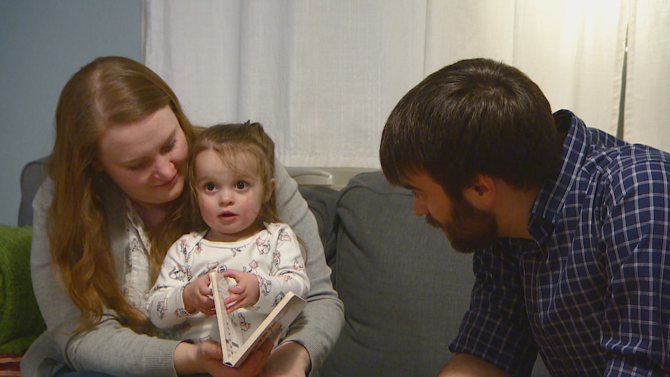 La famille Malenczak-Dunn lit un livre sur le sofa.