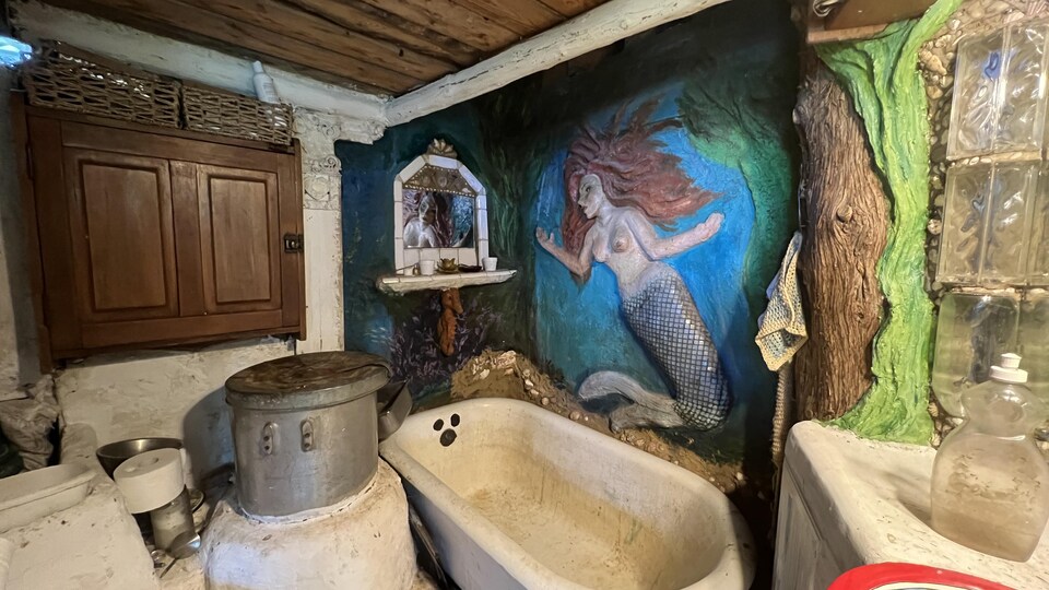 Une sculpture représentant une sirène dans le fond de l'eau recouvre un des murs de la salle de bain. 