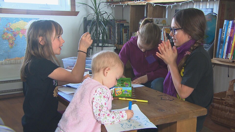 Des enfants autour d'une table qui dessinent et jouent