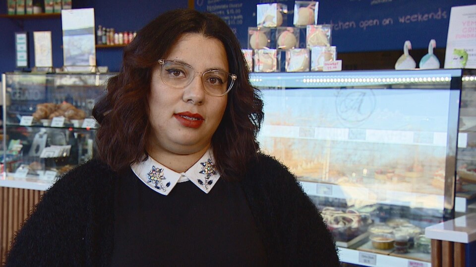 Fatima Zaid is in front of the pastry shop window in her cafe. 