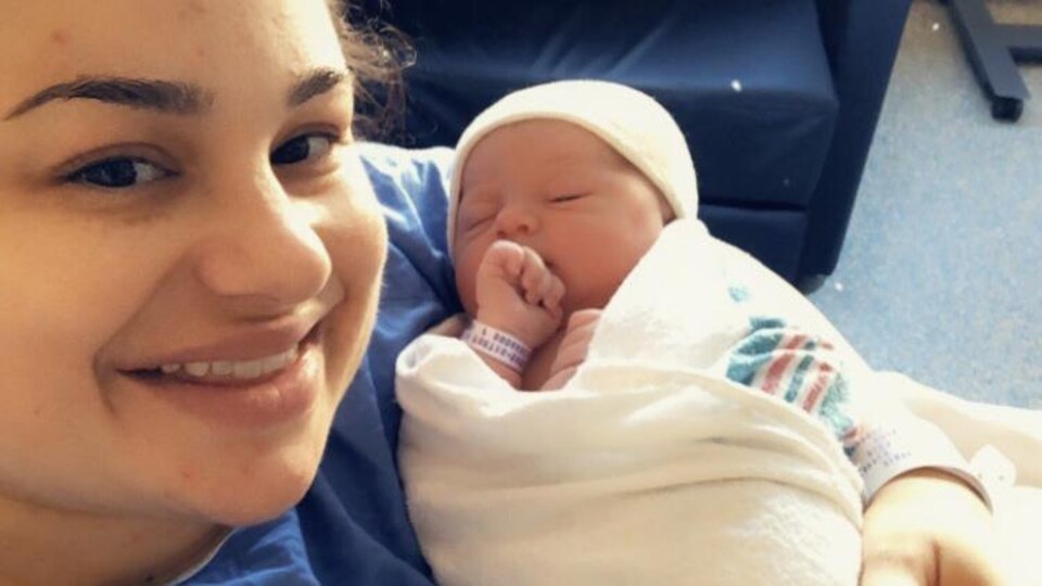 Myriam Fortin-Barbier, souriante, tient sa nouveau-née dans ses bras et pose pour la caméra.