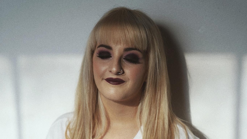 Une femme blonde sourit.