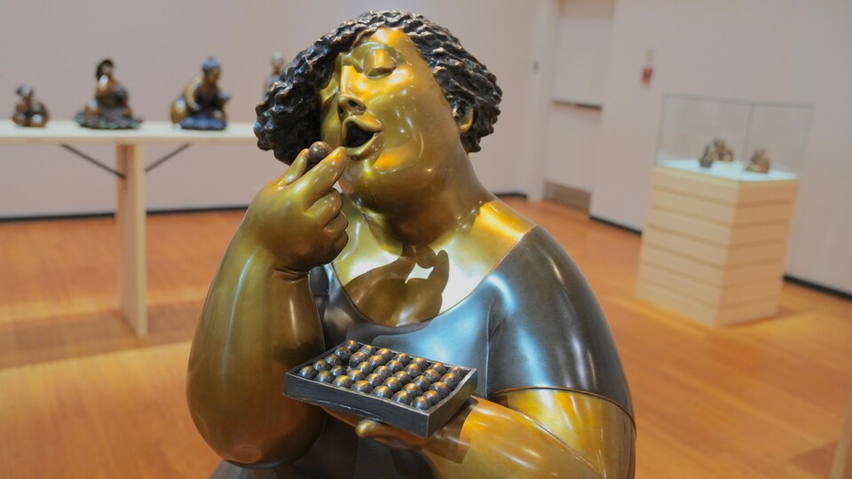 Une sculpture d'une femme qui mange des chocolats.