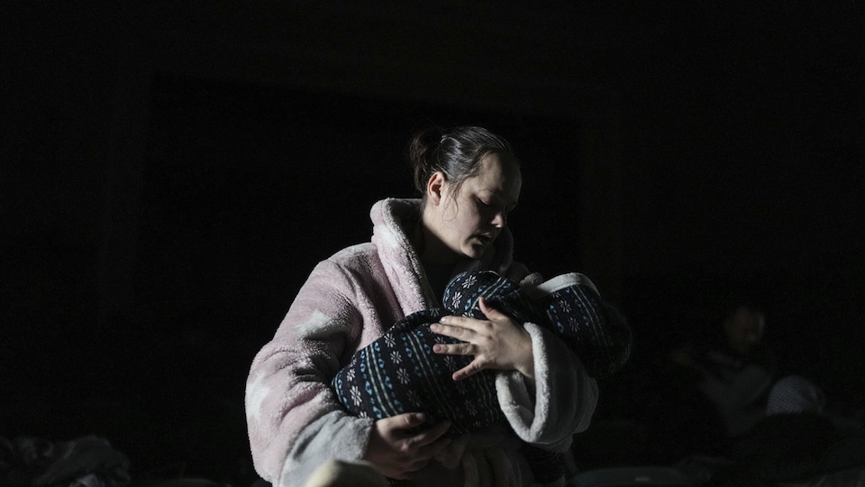 Une femme tient un bébé dans ses mains.