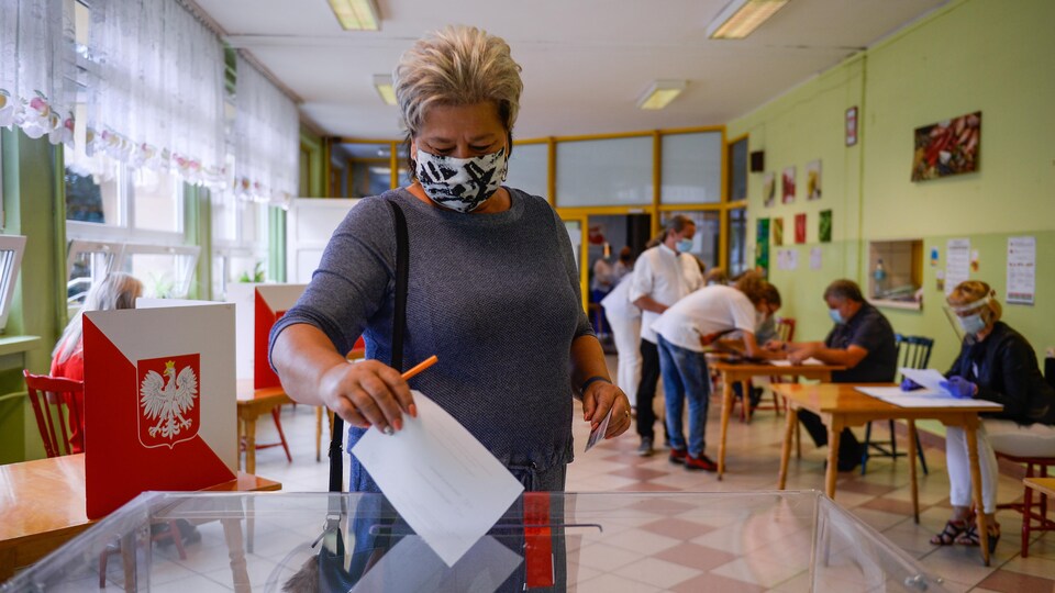 Une femme portant un masque de protection dans un bureau de vote pour le second tour des élections présidentielles polonaises.