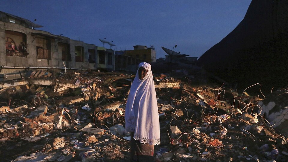 Une femme se tient debout dans les décombres d'un marché détruit par le séisme qui a frappé la province d'Aceh, en Indonésie.