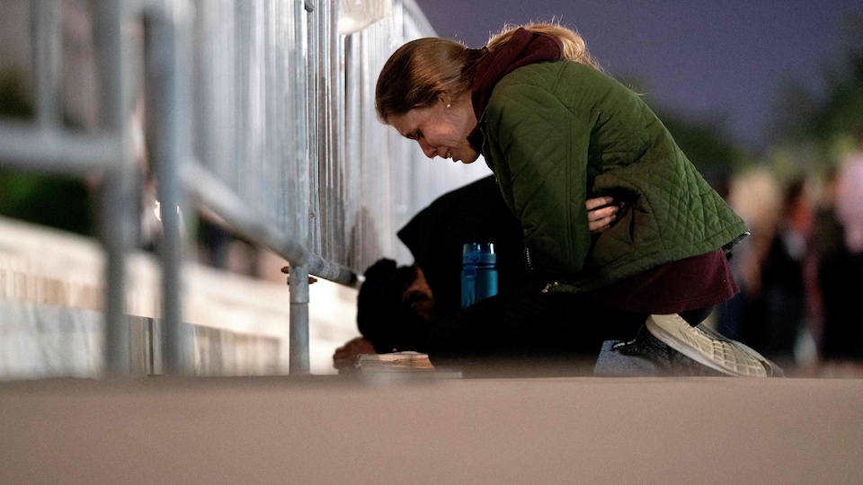 A woman, on her knees, crying.