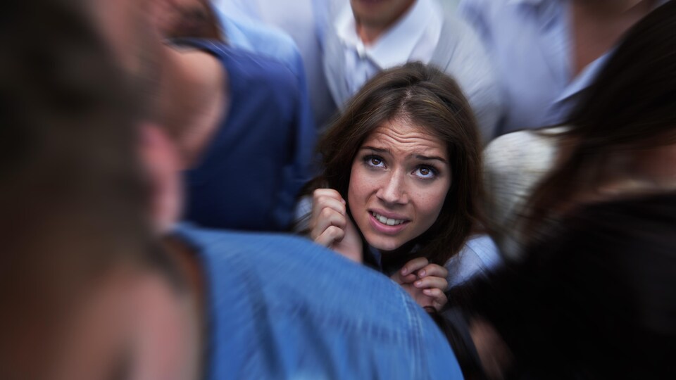 Plan d'une jeune femme craintive piégée par la foule.