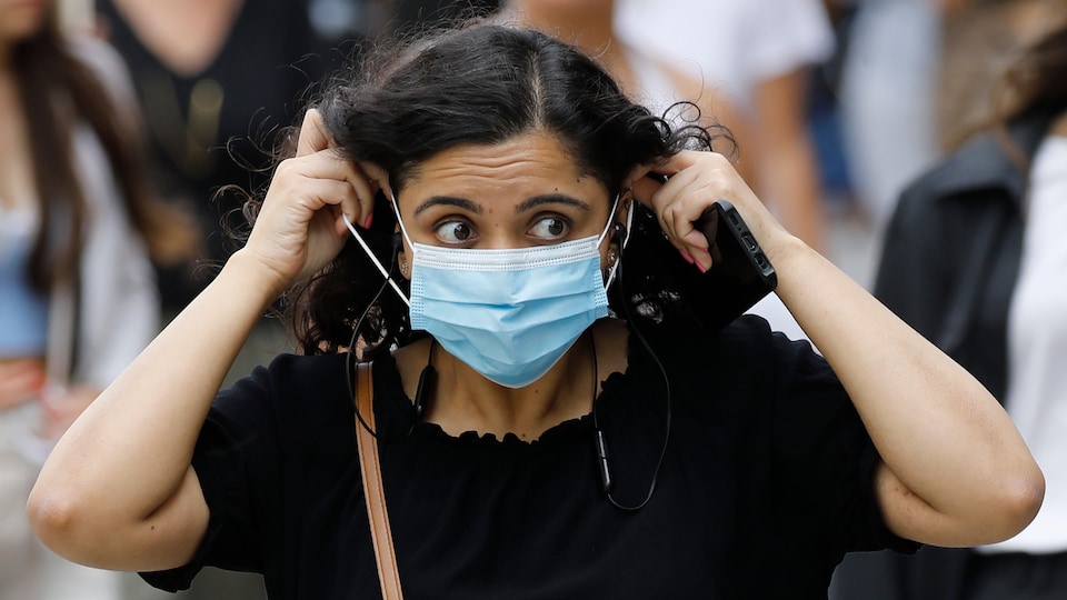 Une femme ajuste son masque facial.