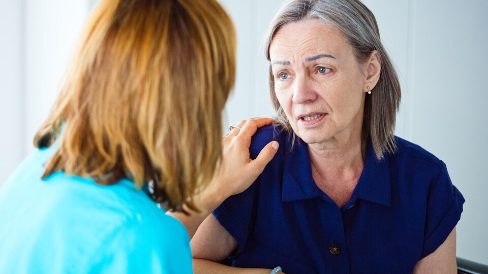 Une femme âgée inquiète parle avec une infirmière. Gros plan du visage.