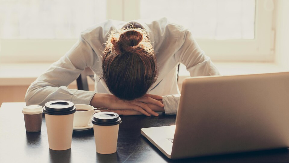 Une femme fatiguée devant un ordinateur.