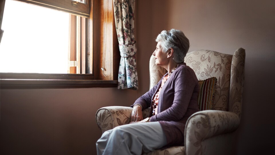 Une femme seule regarde par la fenêtre.