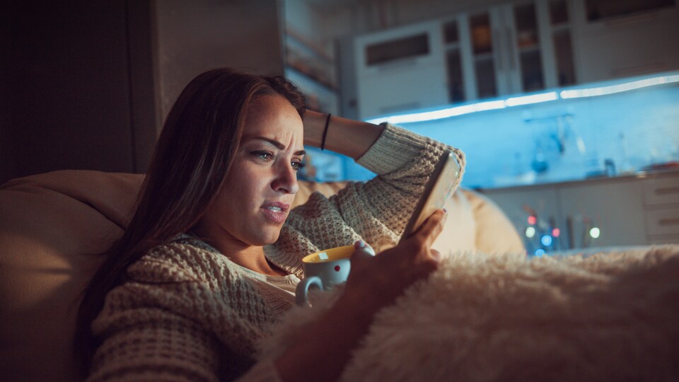 Une femme consulte son téléphone dans son lit la nuit.