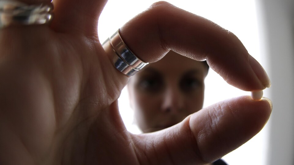 Une femme tient une pilule contraceptive.