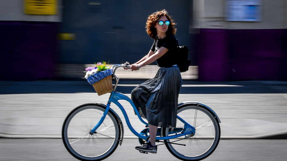 Une femme circule à vélo dans la rue.