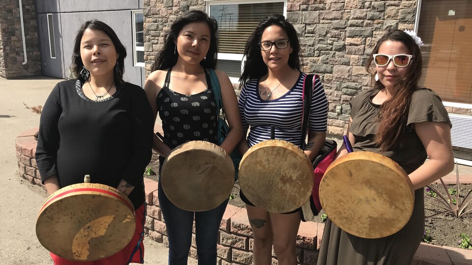 Quatre femmes autochtones portant des tambours traditionnels.