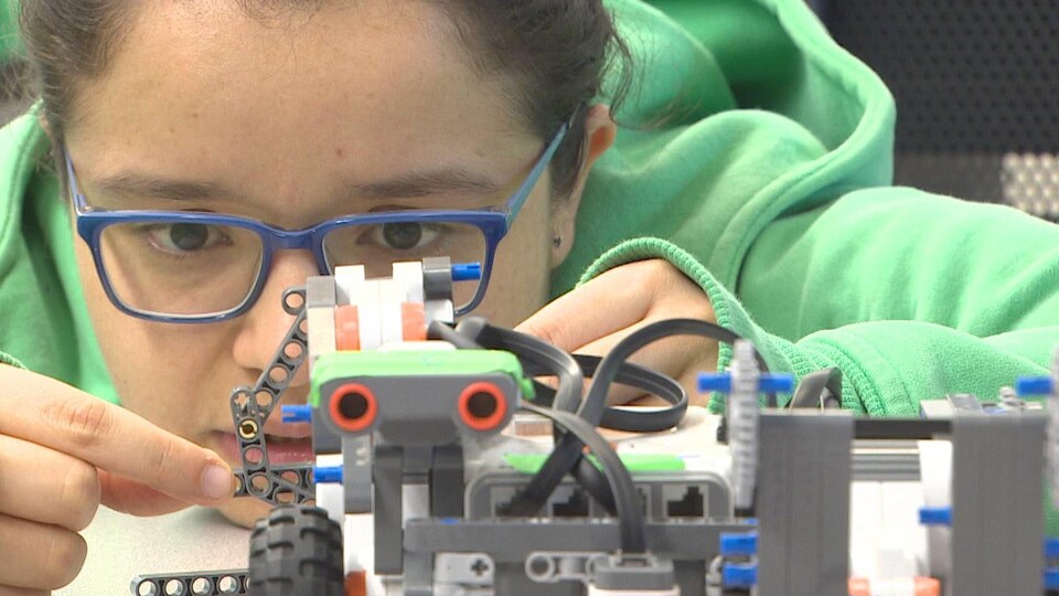 Jeune femme travaillant sur un robot.