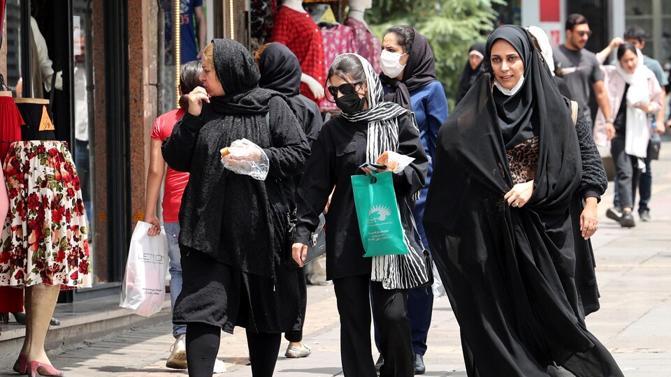 Des femmes qui portent le voile marchent dans la rue.