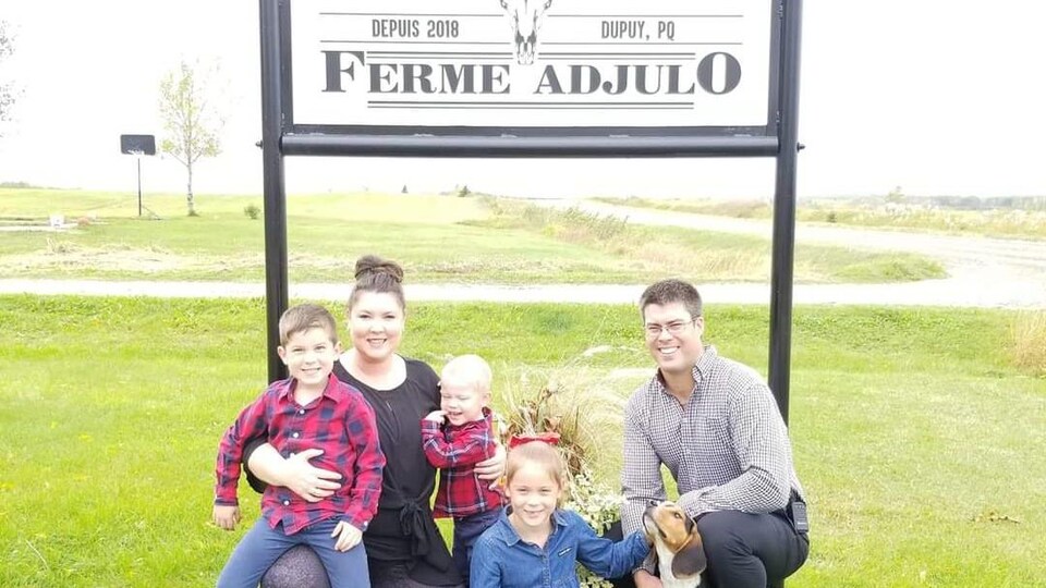 Pierre-Luc Létourneau, sa conjointe, leurs trois enfants et un chien posent près de la pancarte annonçant la ferme Adjulo.