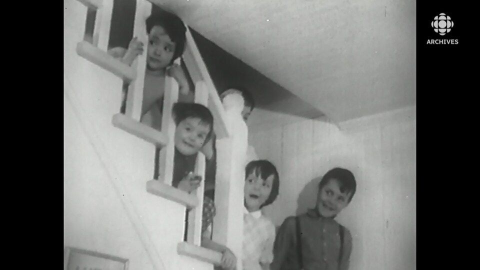 Des enfants posent dans les escaliers d'une ferme familiale.
