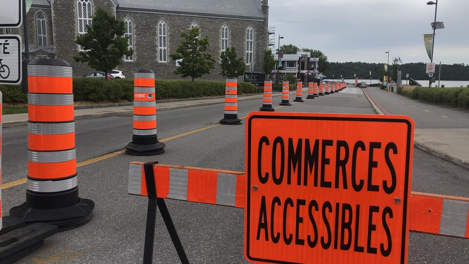 Des cônes orange et des affiches restreignent l'accès à la route.