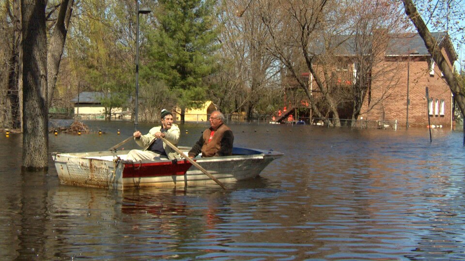 Deux hommes en canot circulent dans un quartier inondé de Gatineau.
