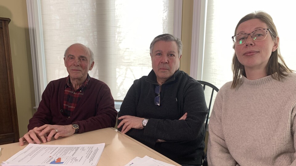 Fernando Boudreau, Jacques Boudreau et Christina Metcalf sont assis à une table de cuisine devant des documents et posent pour une photo.