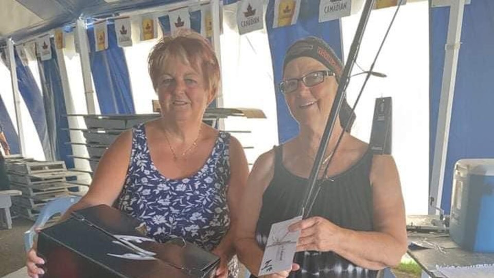 Mme Mcconnell tient une canne à pêche d'une main et un document de l'autre main.