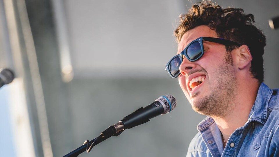 Jonny Arseneau, photographié de près tandis qu'il chante et joue de la guitare.
