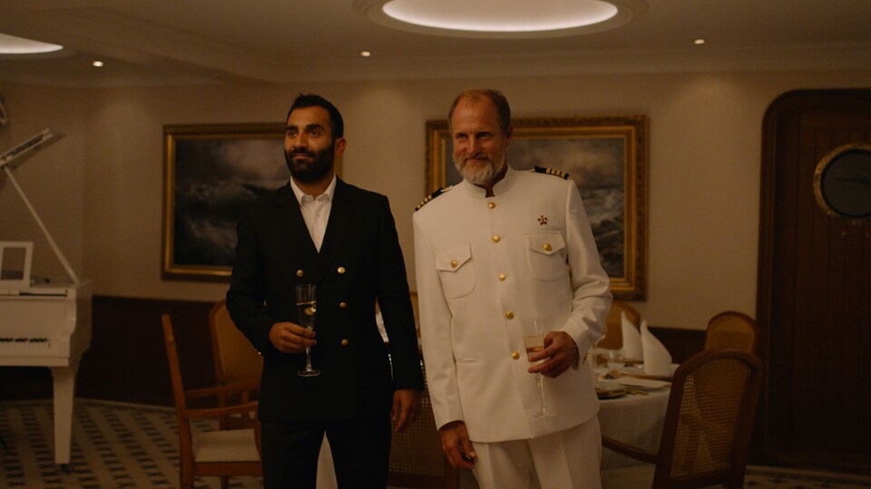 A man in a suit and a captain in a luxurious room.
