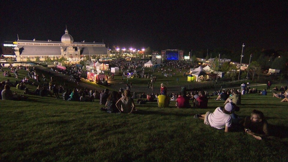 Des amateurs de musique sont assis ou couchés sur le gazon pour assister à un spectacle de la programmation. (Archives)