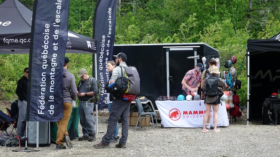 Des amateurs d'escalade discutent devant des tentes d'informations de la Fédération québécoise de la montagne et de l'escalade.