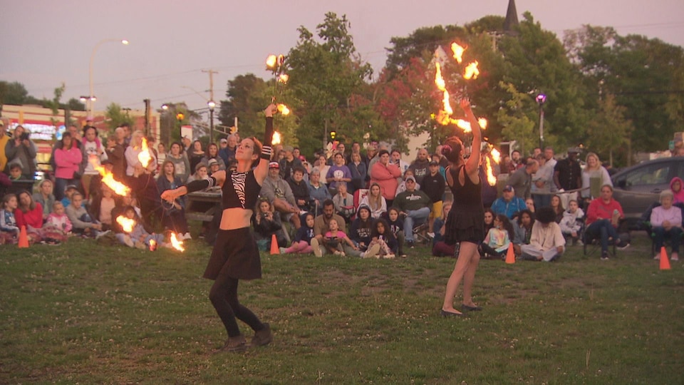 Des artistes dansent avec des cerceaux de feu devant un public.