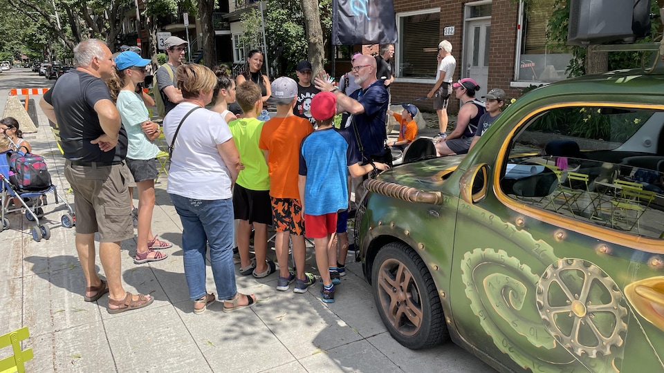 Un magicien donne un spectacle dans une rue de Québec. Il a une voiture avec des dessins artistiques.