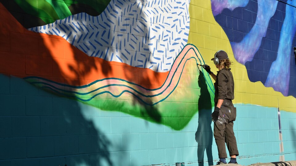 Un artiste en train de peindre une murale.