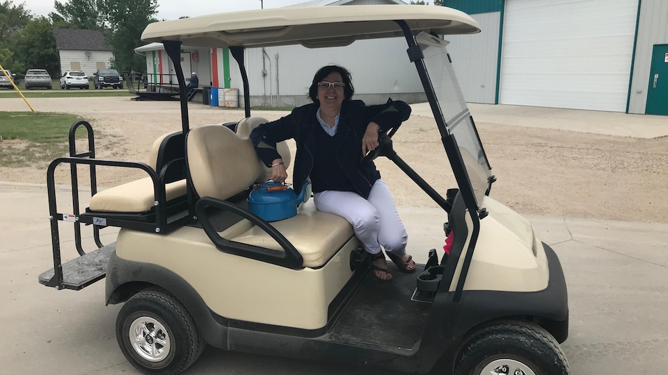 Camille Fisette-Mulaire, souriante et portant des lunettes, est assise dans une voiturette de golf.