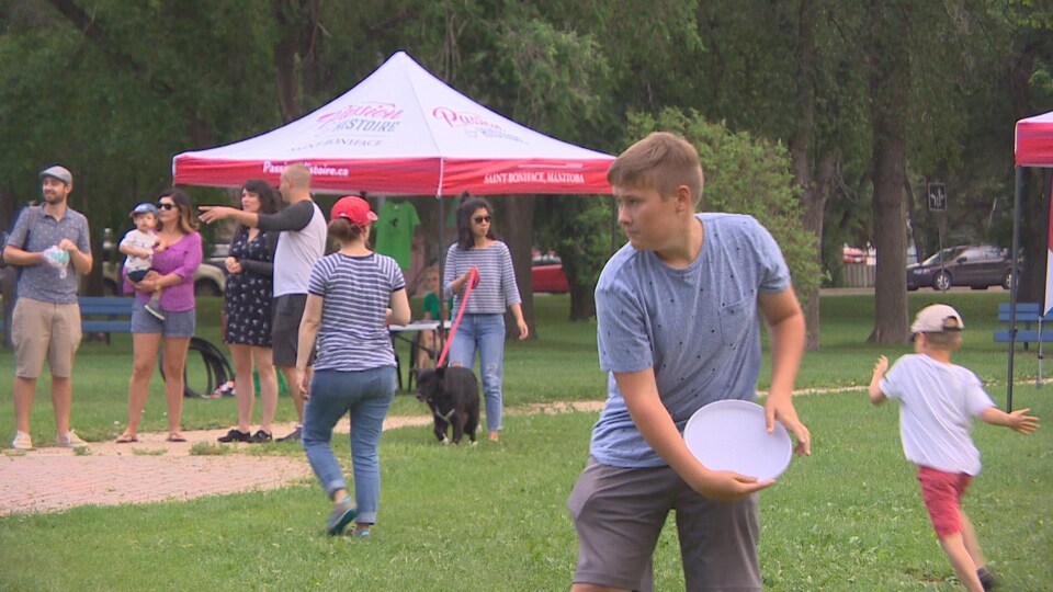 Des personnes jouent dans un parc, devant une petite tente.