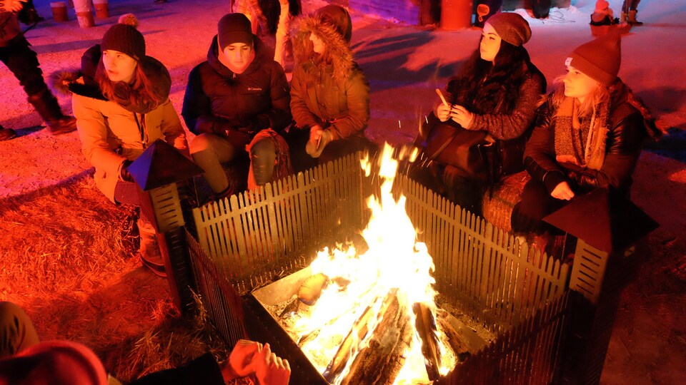 Des jeunes gens assis autour d'un feu extérieur.
