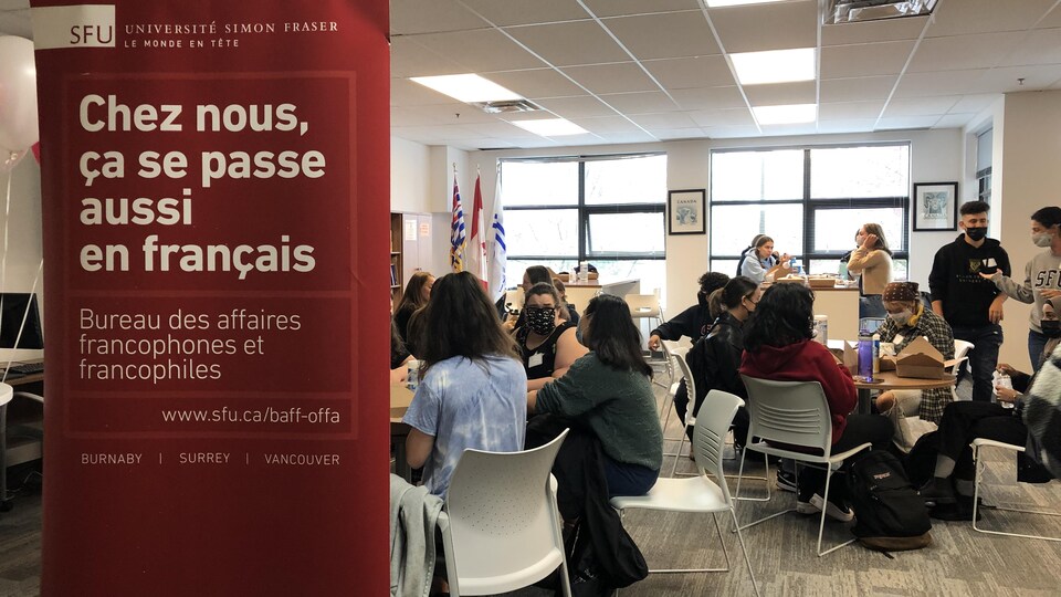 Des étudiants sont assis en petits groupes à des tables, ils dînent et discutent.