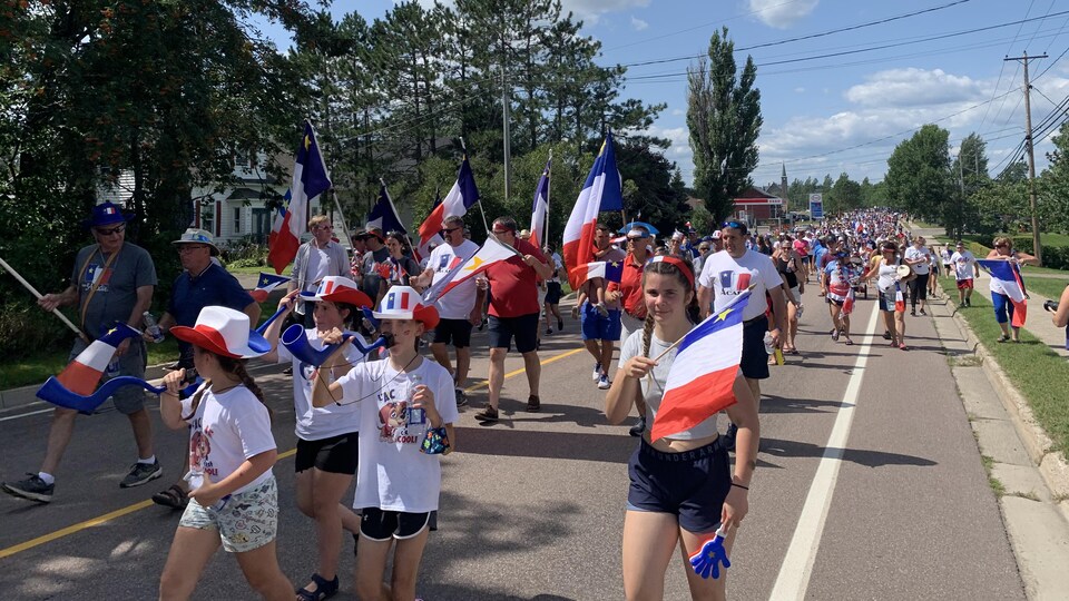 Des gens défilent dans la rue avec des drapeaux de l'Acadie.