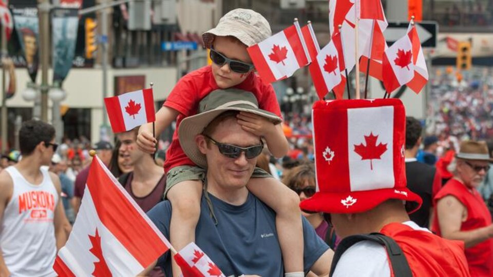 Des gens vêtus en rouge et blanc ainsi que des drapeaux canadiens.