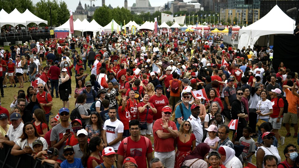 Les gens applaudissent en regardant vers la scène à la fin du spectacle de l'heure du midi lors des célébrations de la Fête du Canada aux plaines Lebreton à Ottawa le 1er juillet 2022.