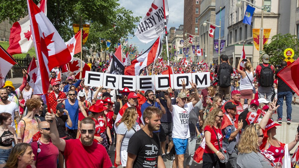 Une foule vêtue de rouge et brandissant des drapeaux canadiens dans la rue
