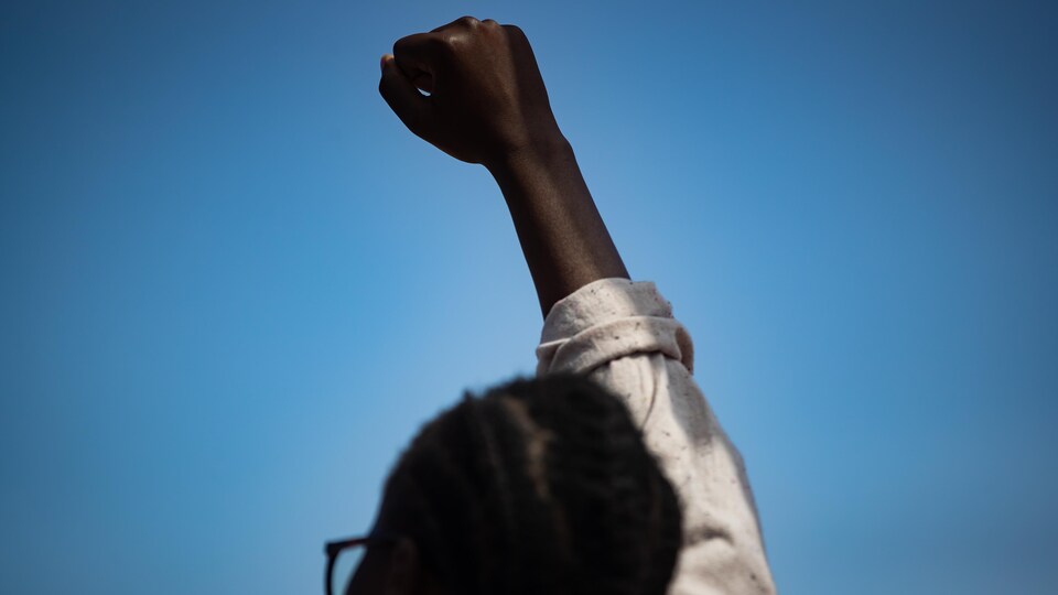 Une personne noire lève le poing en l'air.