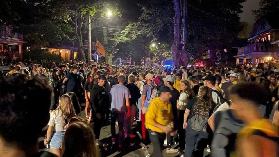 Des dizaines de personnes sont dans la rue, le soir.